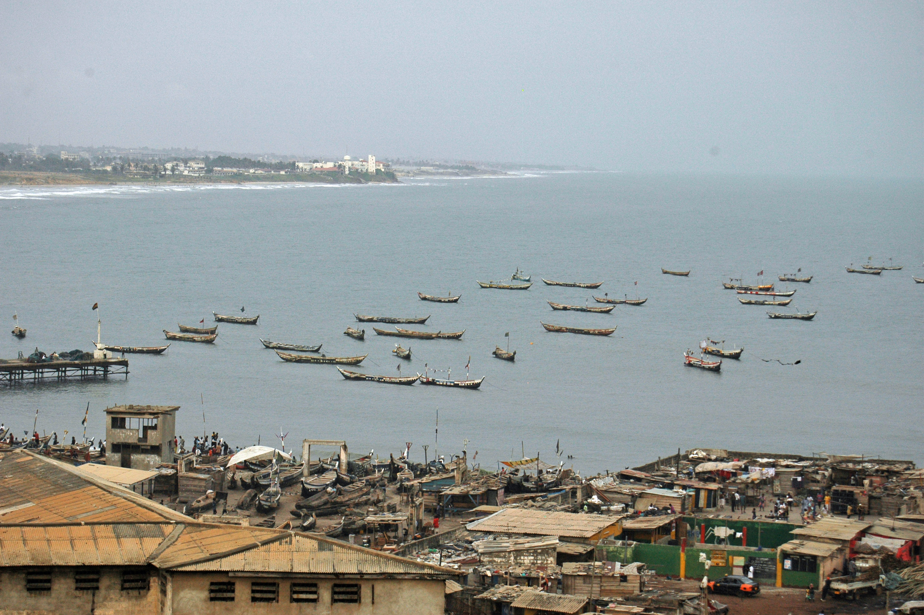 View from the Jamestown lighthouse in 2007 over the roof of James Fort to the sea, fishing boats in the harbour and the white Osu Castle in the distance